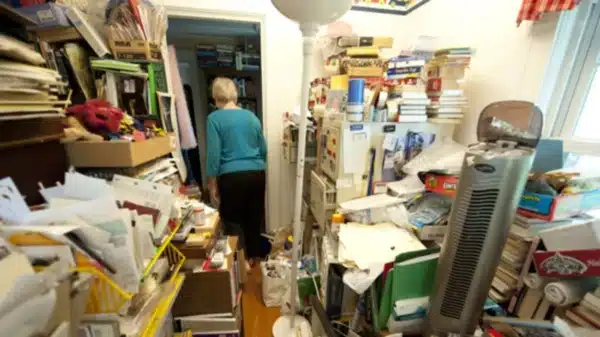 Persona rodeada de objetos acumulados dentro de una vivienda por trastorno de acumulación compulsiva