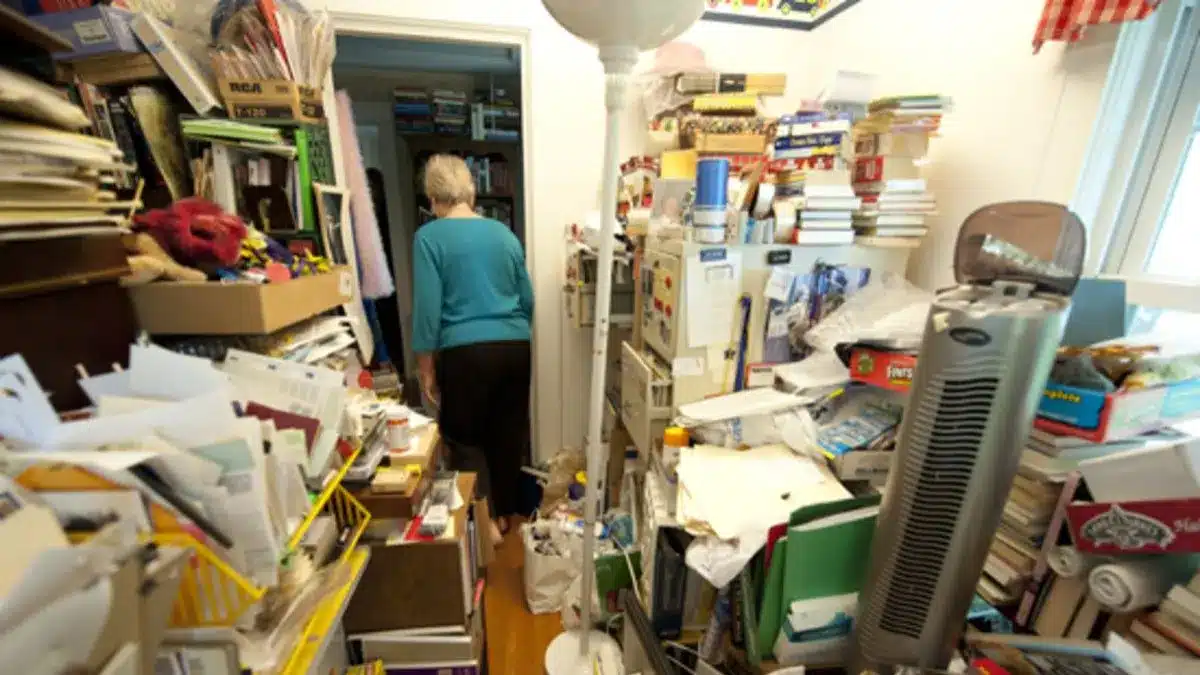 Persona rodeada de objetos acumulados dentro de una vivienda por trastorno de acumulación compulsiva