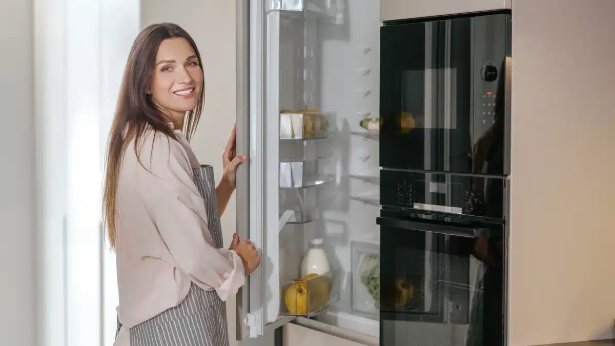 Ama de casa organizando alimentos en su refrigeradora en cocina moderna