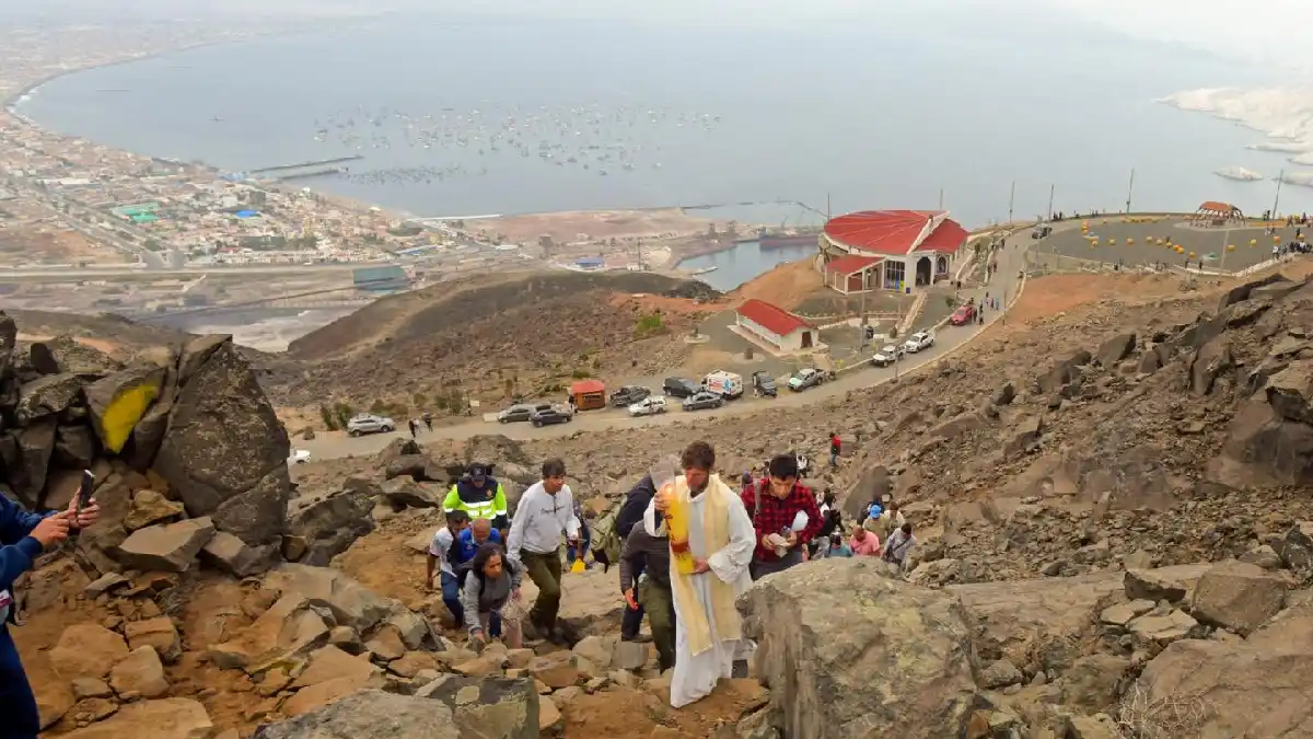 Sacerdote con cirio lidera procesión hacia la iluminación Cruz de la Paz en el cerro de la Juventud en Chimbote