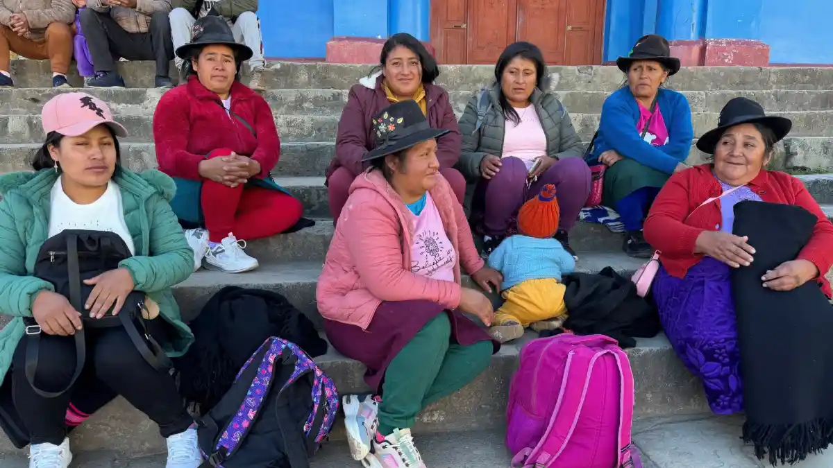 Madres de comedores populares esperan en las gradas de la iglesia de Cabana antes de la convención